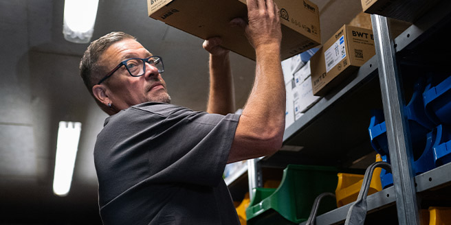 Im Lager der Firma Rolf Müller Haustechnik hebt ein Mitarbeiter einen Karton aus einem Regal