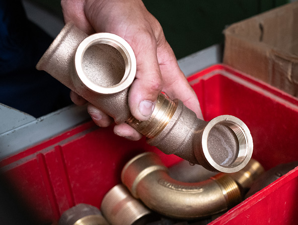 Hand hält eine Sanitärarmatur aus Messing in der Werkstatt der Firma Rolf Müller Haustechnik